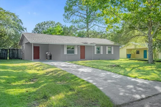 a view of a house with a yard and large tree