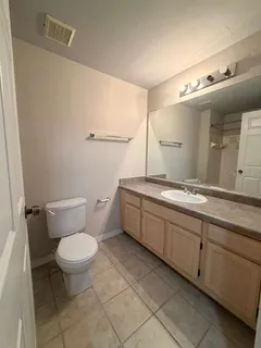a bathroom with a granite countertop sink a mirror and a toilet