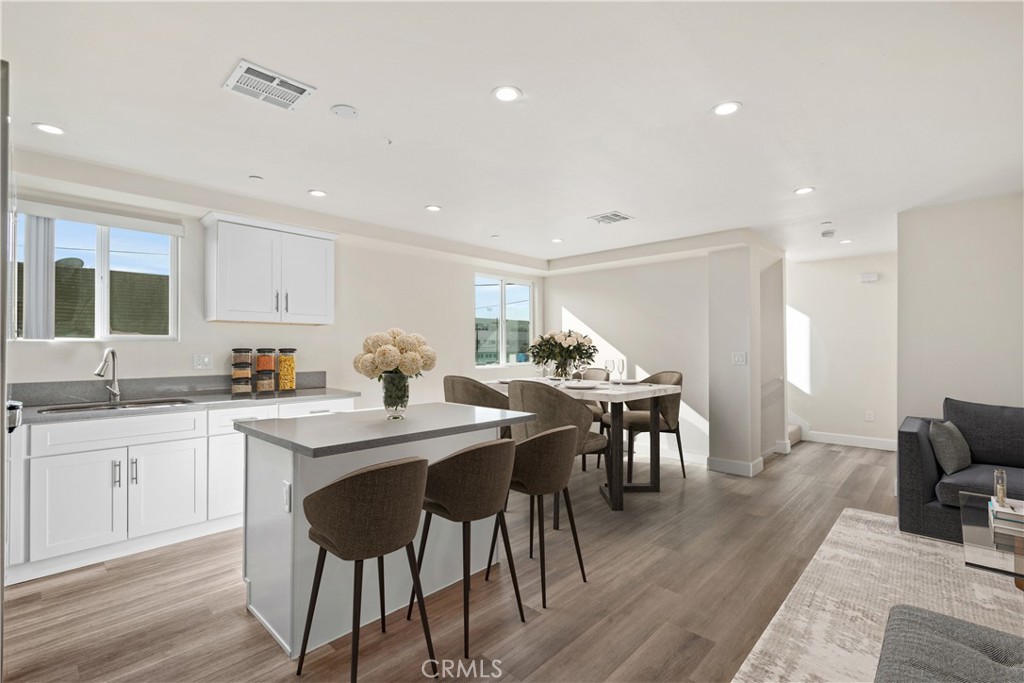 1822 Orchard Avenue, Unit 1822 Los Angeles, CA 90006 - Photo 3 of 17 a kitchen with stainless steel appliances a dining table chairs and wooden floor
