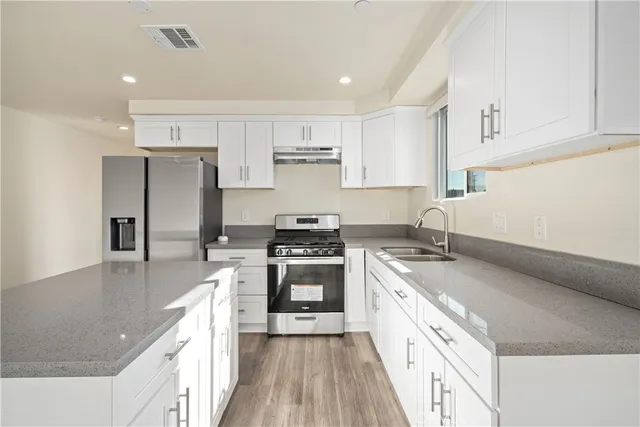 a kitchen with stainless steel appliances granite countertop a sink stove and refrigerator
