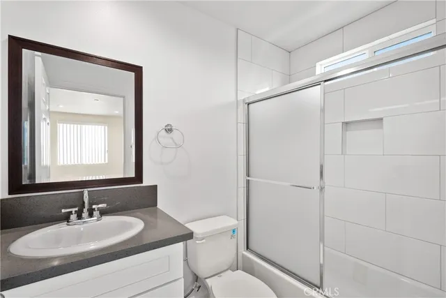 a bathroom with a granite countertop sink toilet a mirror and shower