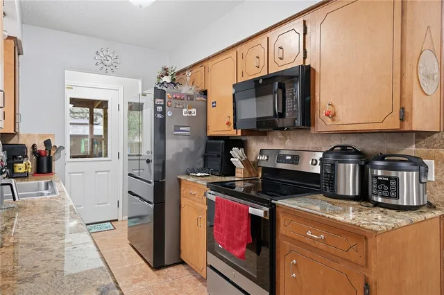 a kitchen with stainless steel appliances granite countertop a stove a sink and a microwave