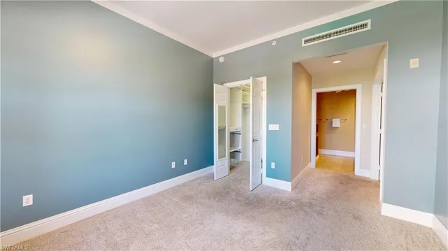 a view of an empty room with closet and a bathroom