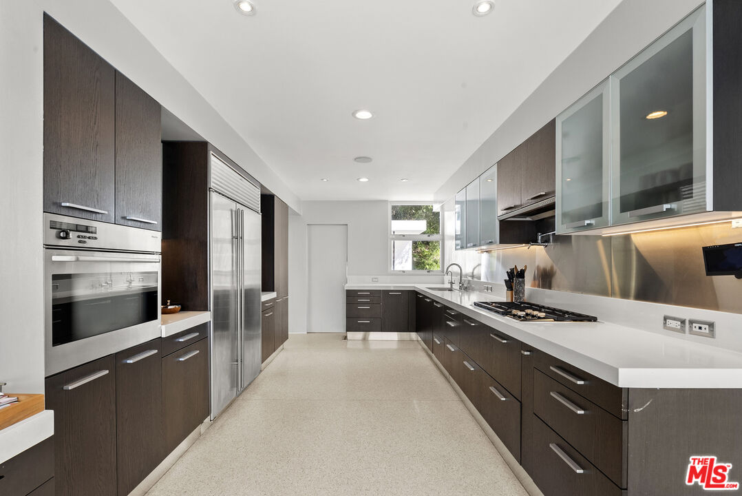 10899 Chalon Road Los Angeles, CA 90077 - Photo 15 of 34 a kitchen with stainless steel appliances a stove sink and cabinets