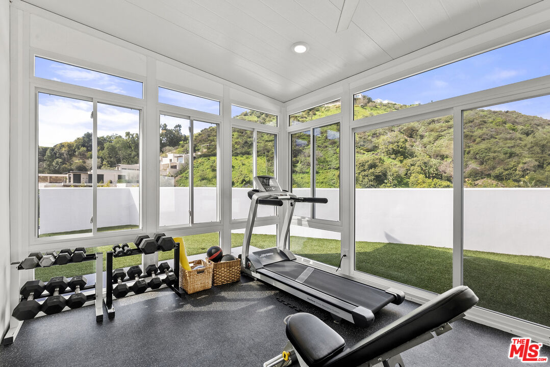 10899 Chalon Road Los Angeles, CA 90077 - Photo 26 of 34 a room with gym equipment and large windows