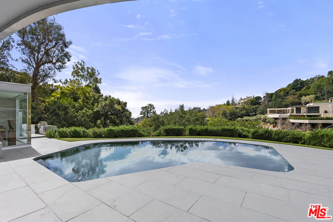 10899 Chalon Road Los Angeles, CA 90077 - Photo 31 of 34 a view of a swimming pool and trees in the background