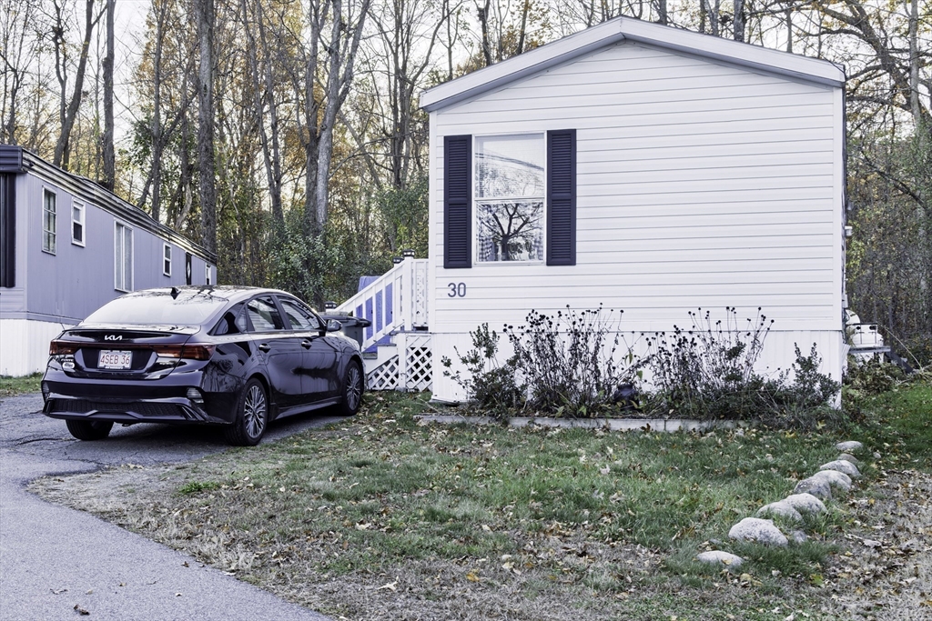 18 Maple Street, Unit 30 Pepperell, MA 01463 - Photo 17 of 19 a front view of a house with a garden and parking space
