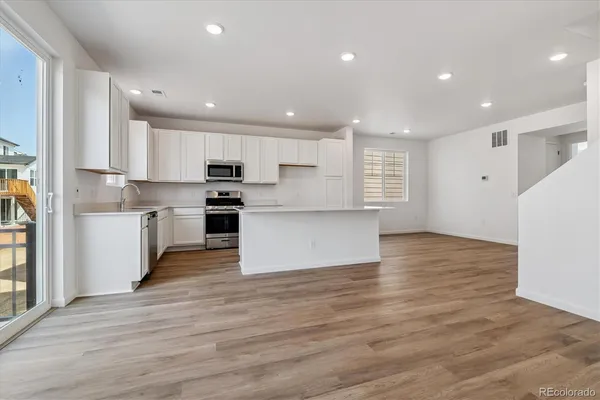 a view of kitchen view wooden floor stainless steel appliances and cabinets