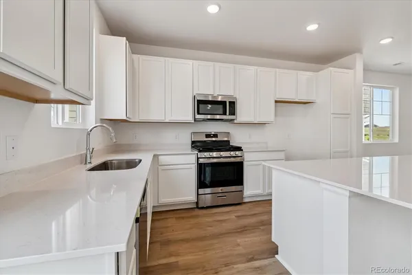 a kitchen with stainless steel appliances a stove a sink a microwave a refrigerator and cabinets