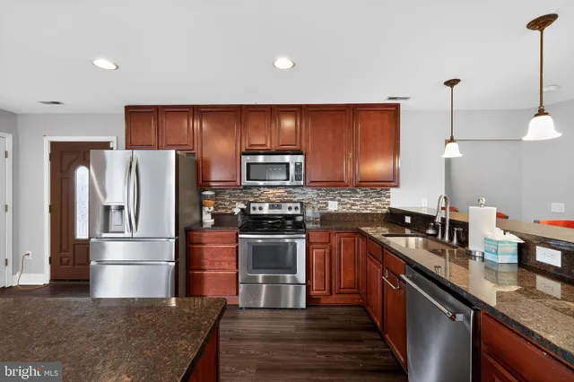 a kitchen with granite countertop stainless steel appliances and wooden cabinets