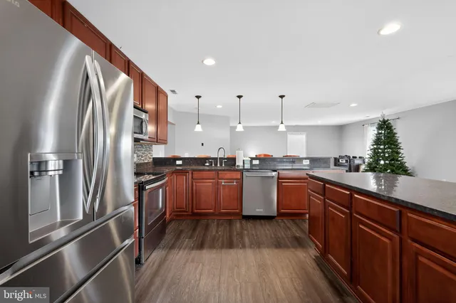 a kitchen with granite countertop a refrigerator a sink dishwasher and white cabinets with wooden floor