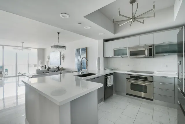 a kitchen with stainless steel appliances a sink a stove a microwave a center island and cabinets