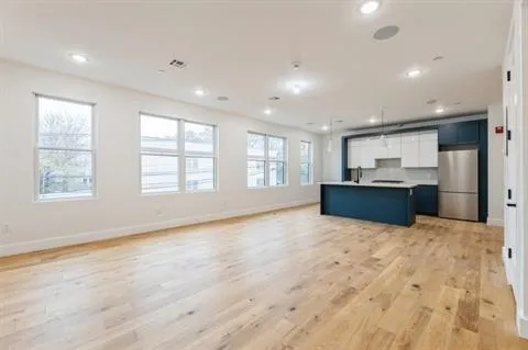 a view of an empty room with a window and kitchen view