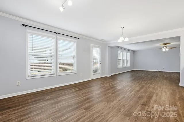 a view of empty room with wooden floor and kitchen