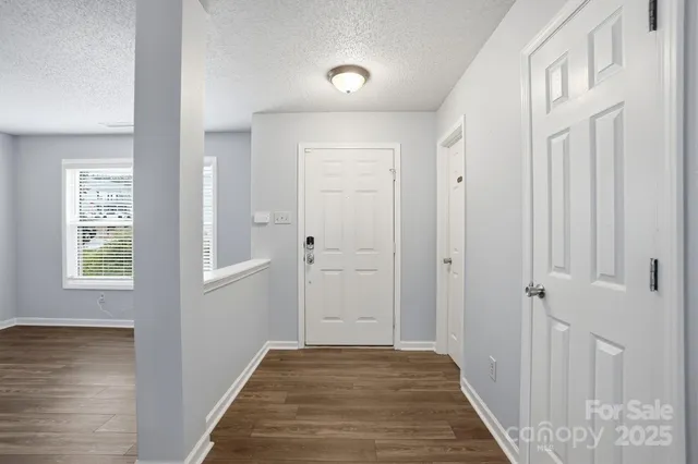 a view of a hallway with wooden floor and a bathroom