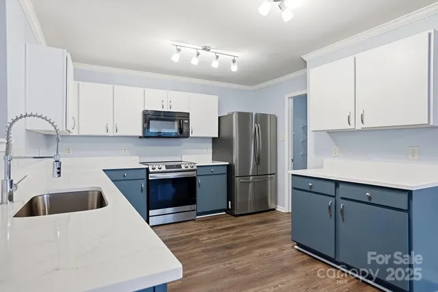 a large kitchen with stainless steel appliances granite countertop a sink and dishwasher a stove top oven with wooden floor