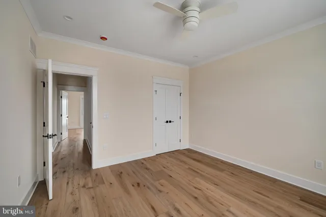 an empty room with wooden floor and a ceiling fan