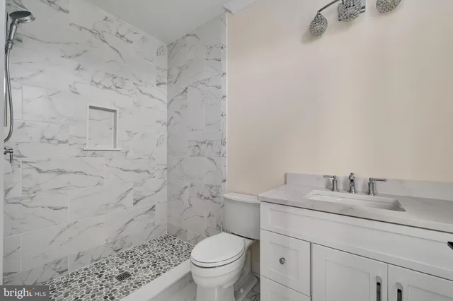 a bathroom with a granite countertop toilet sink and mirror