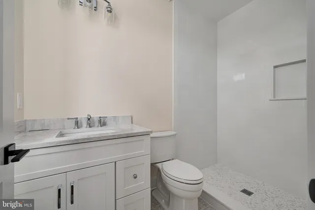 a bathroom with a granite countertop sink a toilet and a mirror