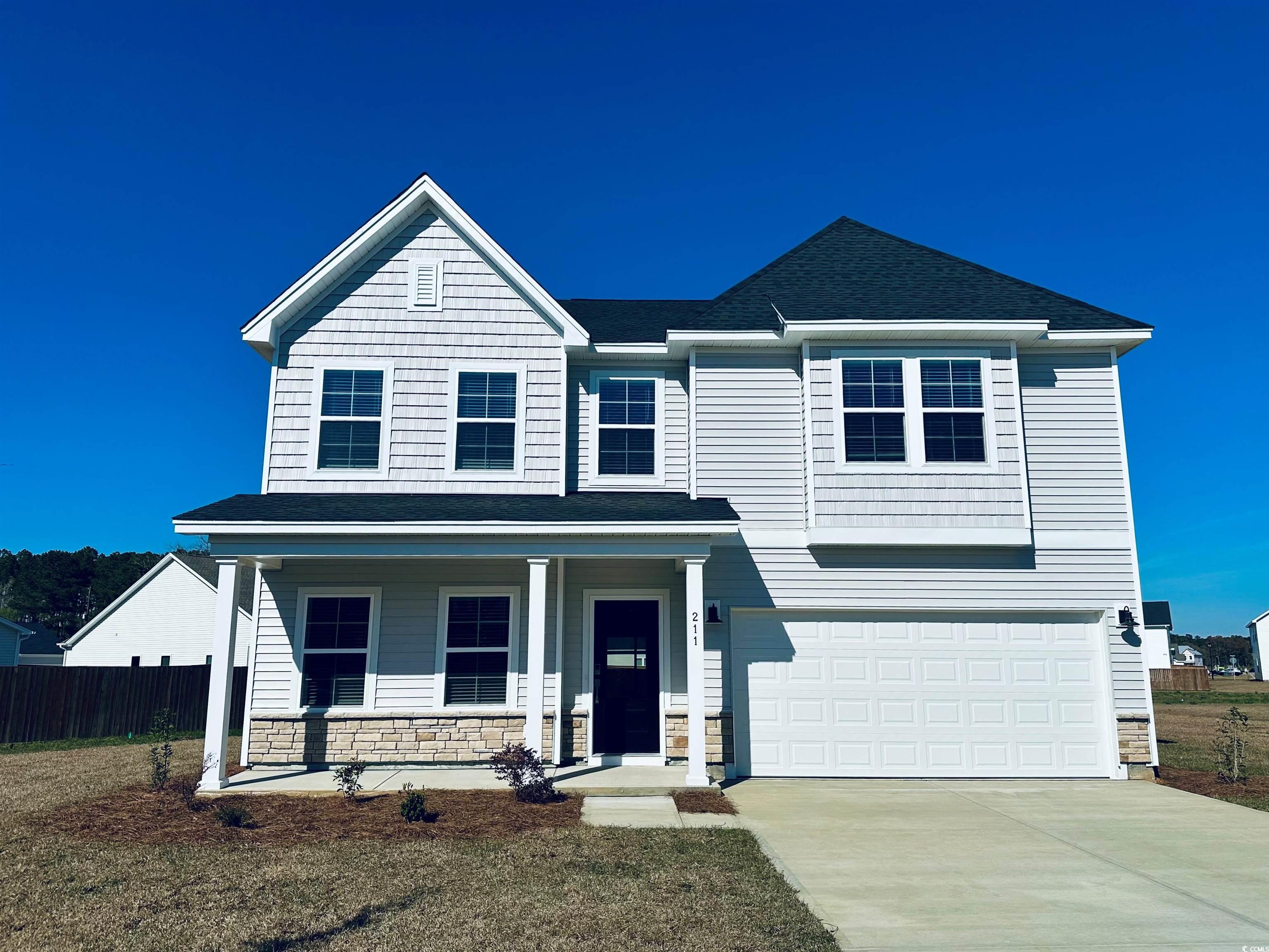 View of front of home with stone siding, a front lawn, a shingled roof, an attached garage, and driveway
