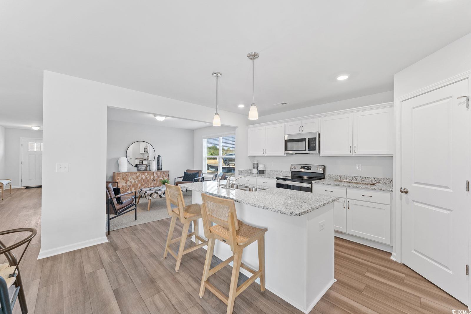 211 Sundrop Way Conway, SC 29526 - Photo 7 of 10 Kitchen featuring hanging light fixtures, white cabinets, stainless steel appliances, light stone countertops, and a center island with sink