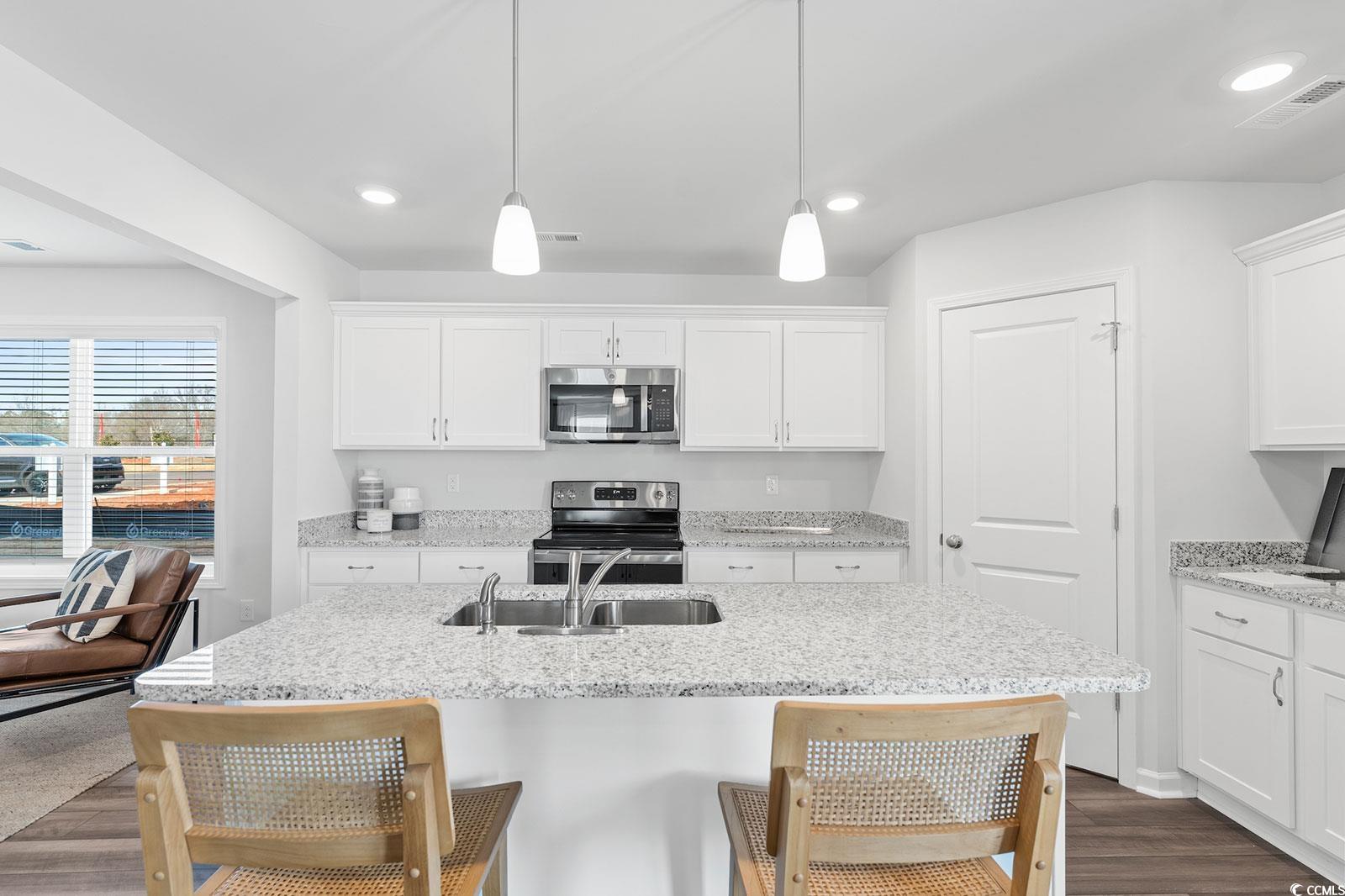 211 Sundrop Way Conway, SC 29526 - Photo 8 of 10 Kitchen featuring white cabinetry, stainless steel appliances, a kitchen bar, dark wood-type flooring, and light stone countertops