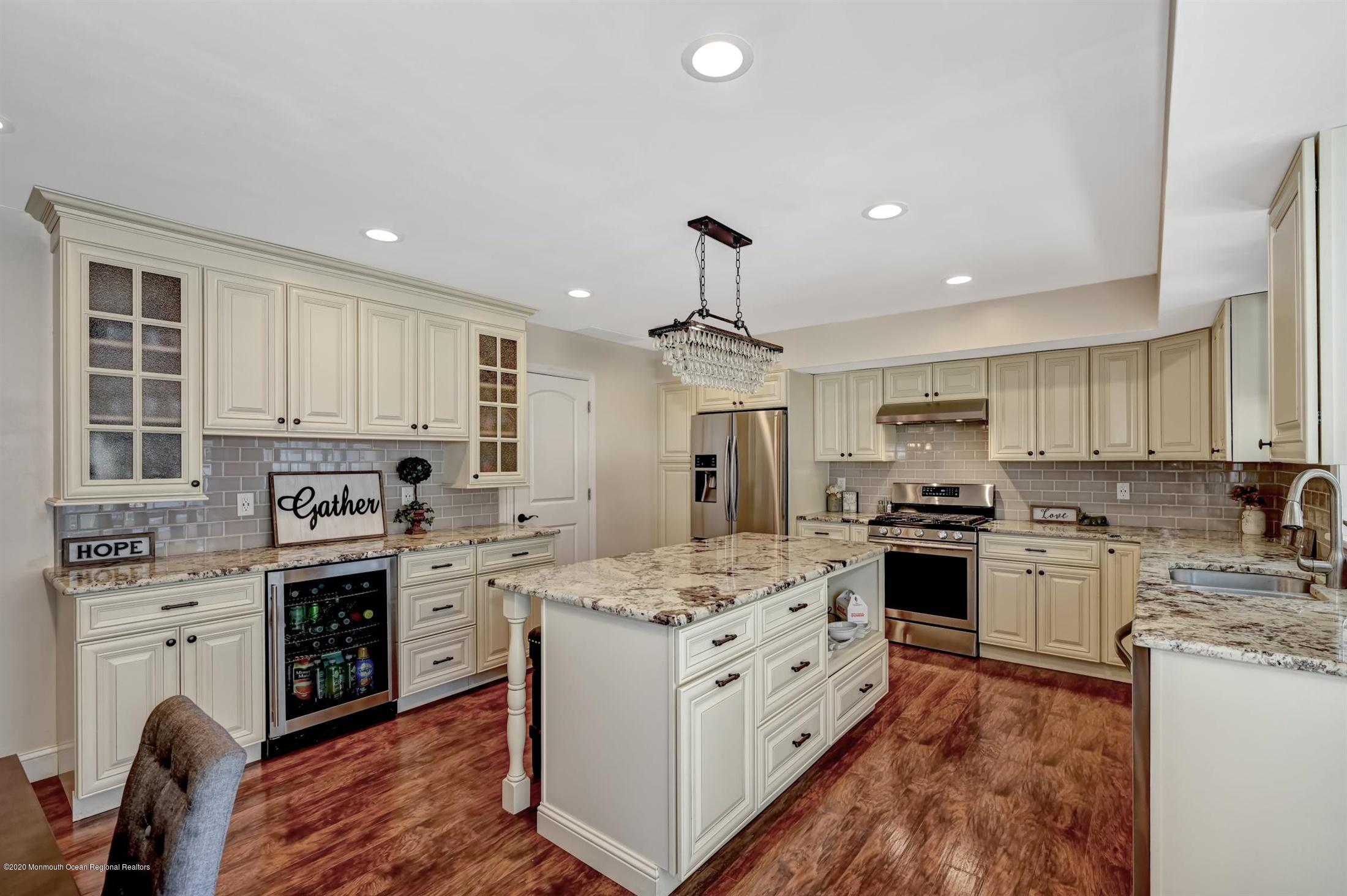 27 Sugar Bush Road Howell, NJ 07731 - Photo 18 of 46 a kitchen with stainless steel appliances granite countertop a stove top oven a sink dishwasher a refrigerator and a dining table with wooden floor
