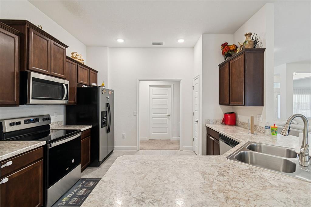 10358 Musa Road Spring Hill, FL 34608 - Photo 17 of 48 a kitchen with stainless steel appliances granite countertop a sink stove and refrigerator