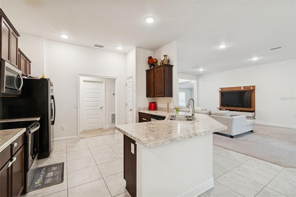 10358 Musa Road Spring Hill, FL 34608 - Photo 18 of 48 a living room with stainless steel appliances furniture a flat screen tv and a view of kitchen
