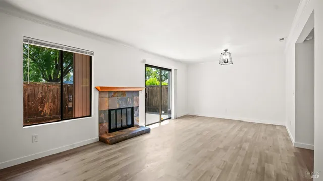 an empty room with wooden floor fireplace and windows