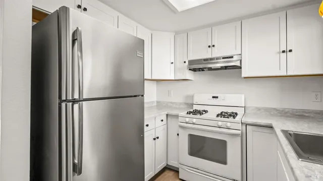 a kitchen with stainless steel appliances white cabinets and a refrigerator