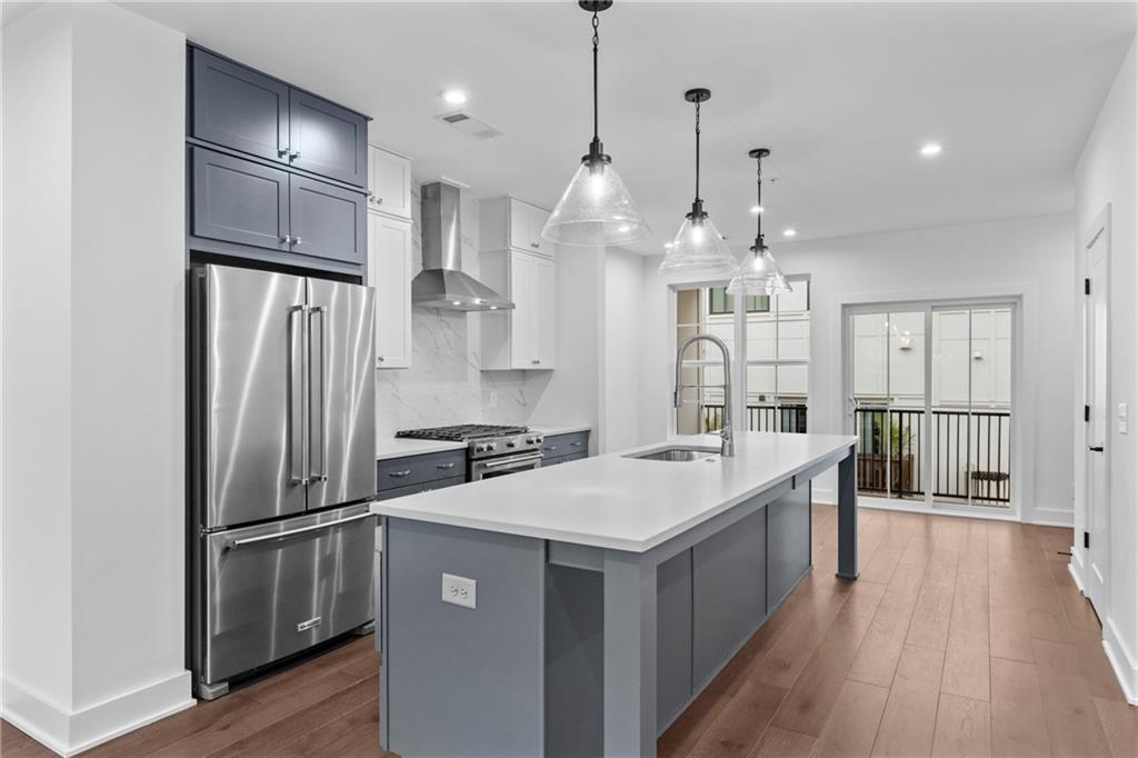 a large kitchen with stainless steel appliances a refrigerator oven a sink dishwasher and a dining table with wooden floor