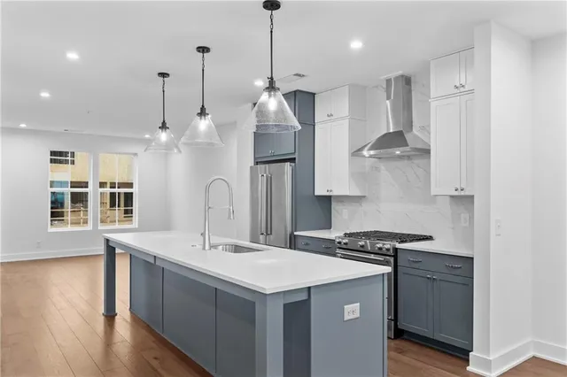 a kitchen with stainless steel appliances granite countertop a sink a stove a refrigerator and island with wooden floor