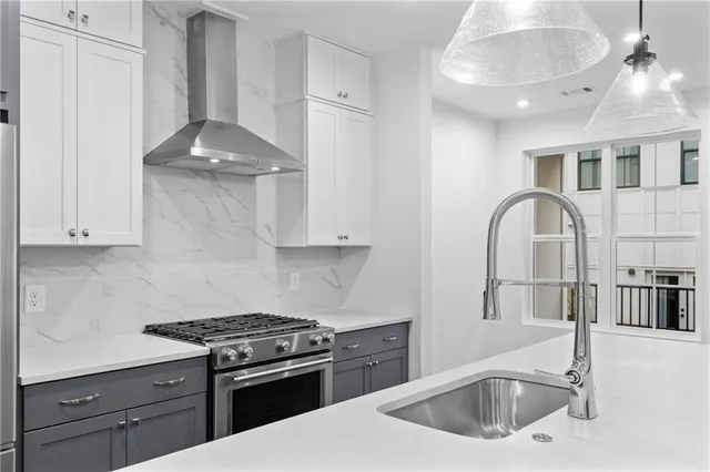 a kitchen with stainless steel appliances granite countertop a sink a stove and a wooden cabinets