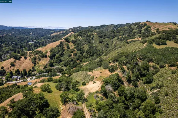 an aerial view of a houses with a lush green hillside