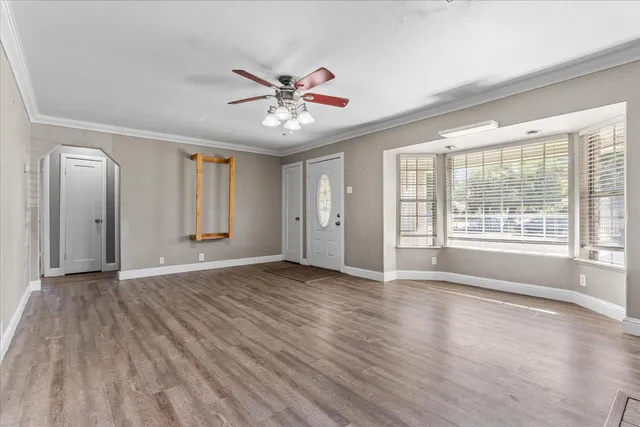 a view of an empty room with a window and wooden floor