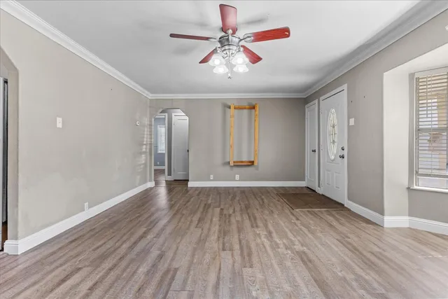 an empty room with wooden floor chandelier fan and windows