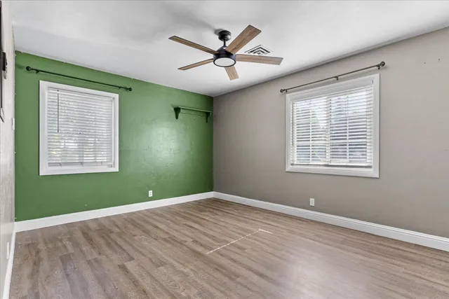 a view of a room with window ceiling fan and hardwood floor