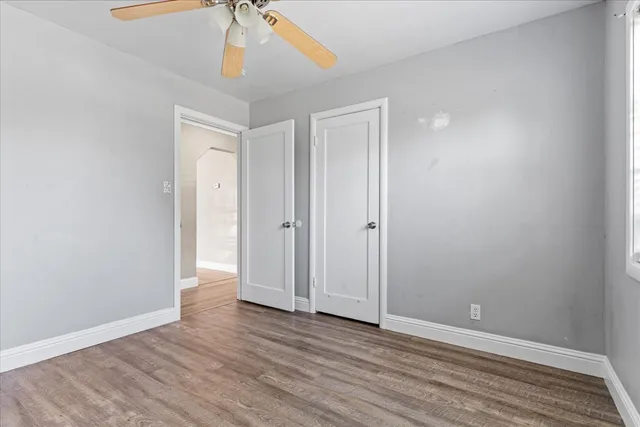 a view of an empty room with window and wooden floor