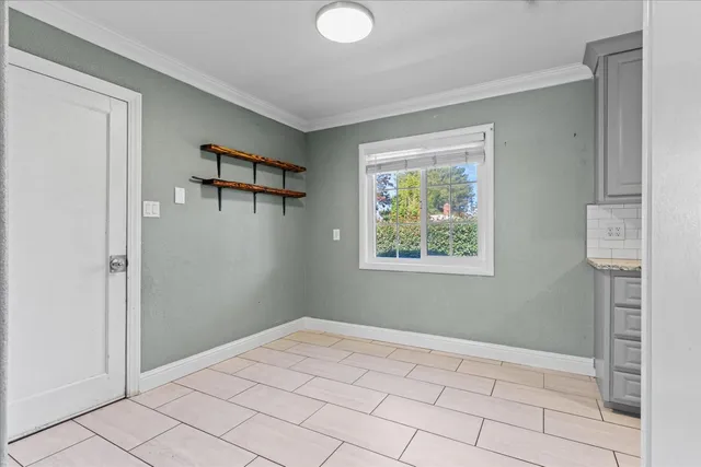 a view of an empty room with window and chandelier fan