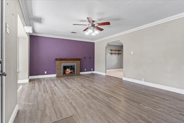 a view of an empty room with wooden floor fireplace and a window
