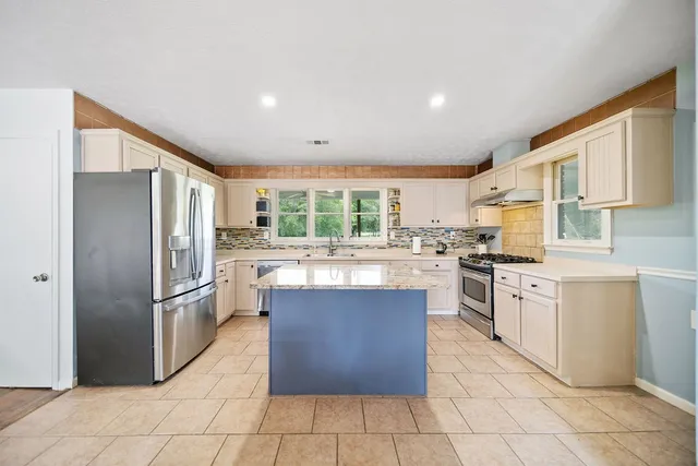 a kitchen with stainless steel appliances granite countertop a refrigerator and a stove top oven