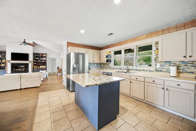 a large kitchen with kitchen island a sink stove and cabinets
