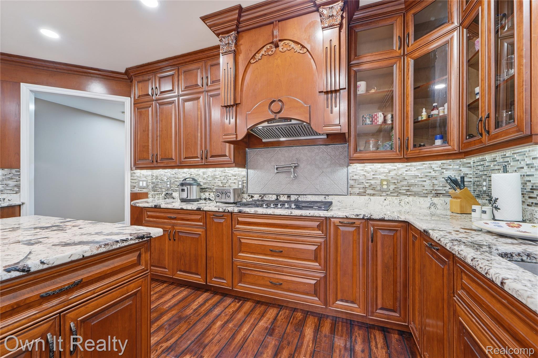 48280 Gladstone Road Canton, MI 48188 - Photo 17 of 59 Kitchen featuring rich wood cabinetry, granite countertops, a gas cooktop with an ornate range hood, glass-front upper cabinets, and a mosaic tile backsplash