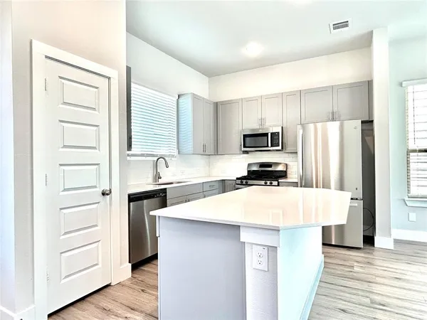 a kitchen with kitchen island a refrigerator stove and sink