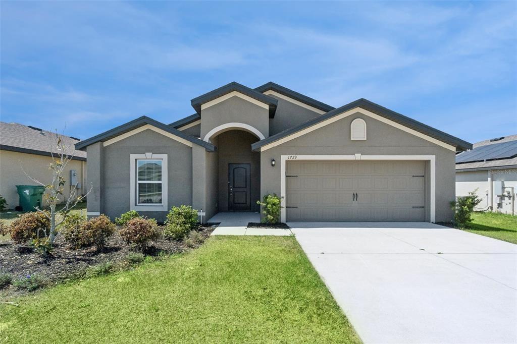 1729 Canaan Loop Dundee, FL 33838 - Photo 2 of 33 a front view of a house with a yard and garage