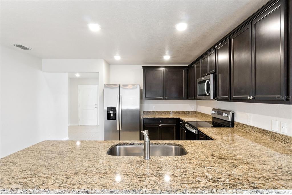 1729 Canaan Loop Dundee, FL 33838 - Photo 9 of 33 a kitchen with stainless steel appliances granite countertop a sink and a refrigerator
