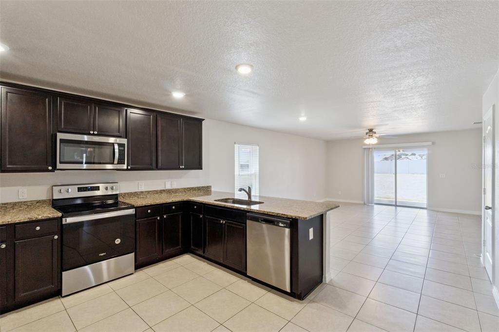1729 Canaan Loop Dundee, FL 33838 - Photo 10 of 33 a kitchen with stainless steel appliances granite countertop a sink counter space cabinets and a large window