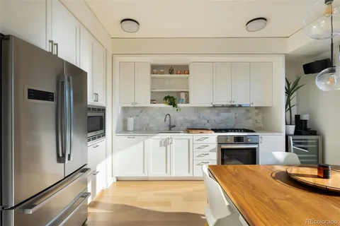 a kitchen with stainless steel appliances granite countertop a refrigerator a stove and a sink