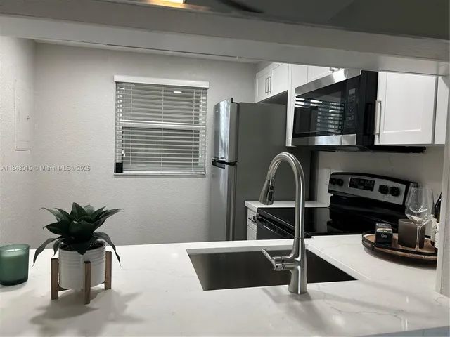 a kitchen with stainless steel appliances kitchen island granite countertop a refrigerator and a stove top oven